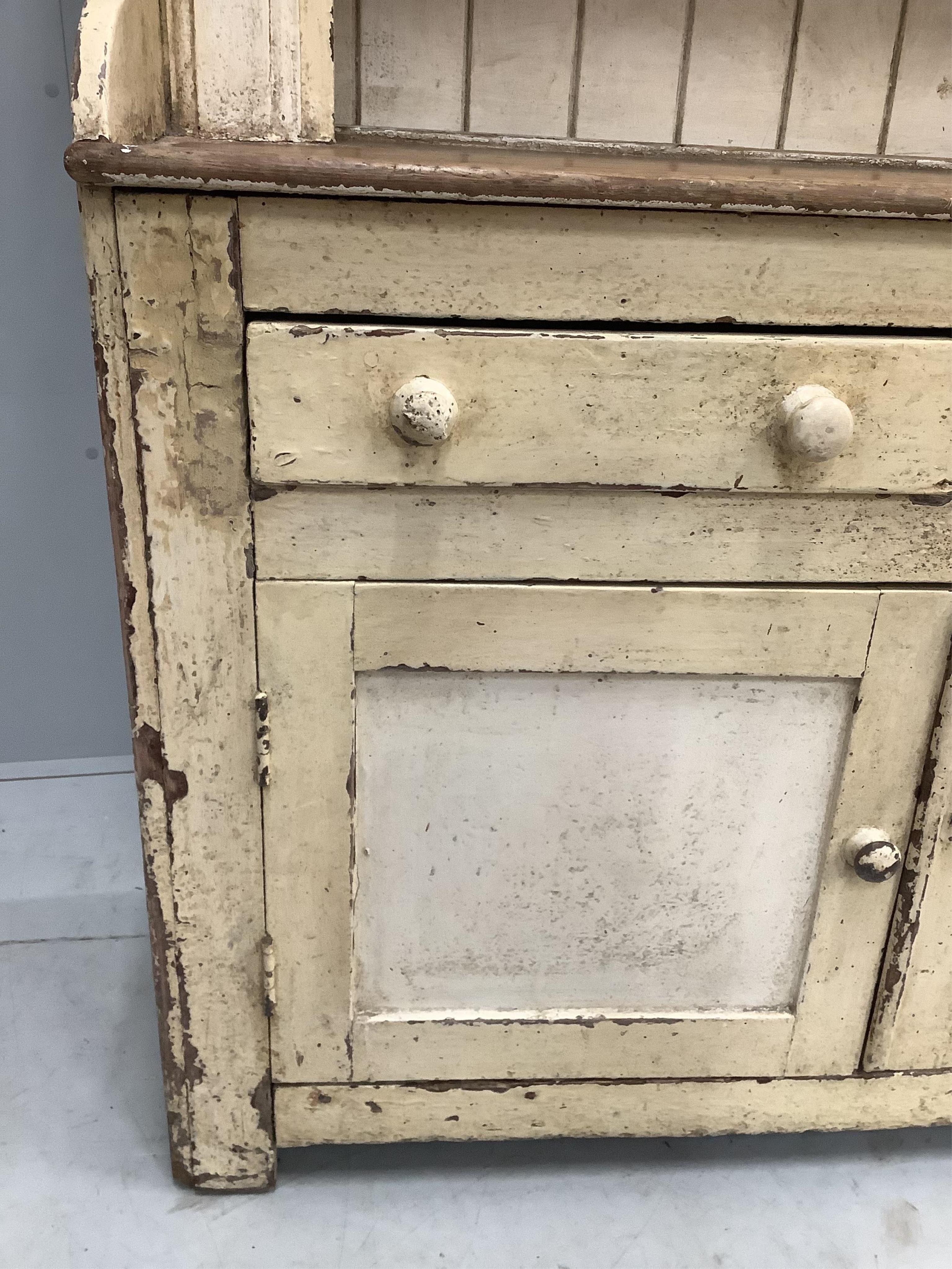 An early 19th century Irish painted pine dresser with boarded rack, width 126cm, depth 49cm, height 210cm. Condition - fair